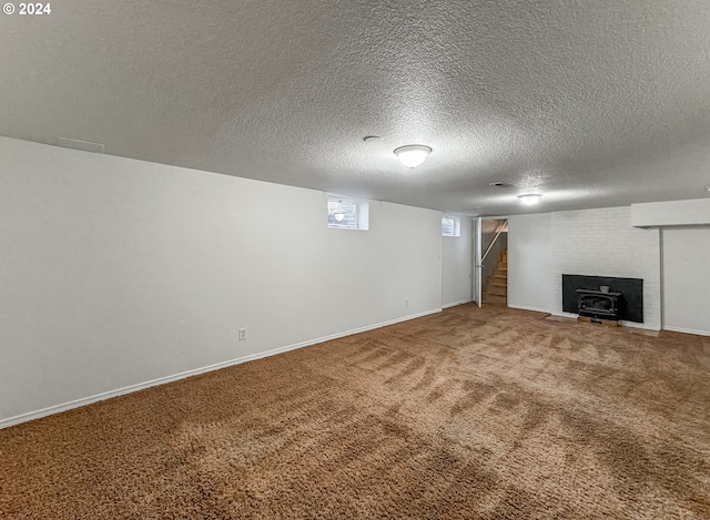 unfurnished living room featuring carpet floors, a textured ceiling, a wood stove, and a brick fireplace