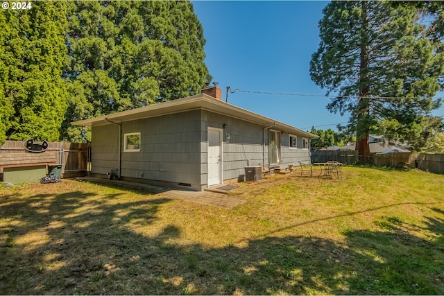 back of house featuring central AC unit and a yard