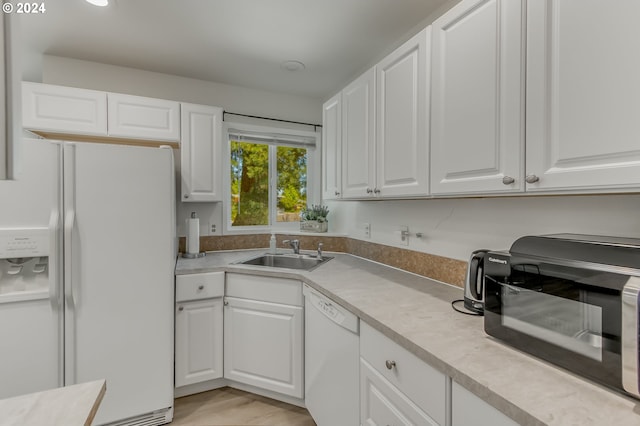 kitchen featuring white appliances, sink, white cabinets, and light hardwood / wood-style floors