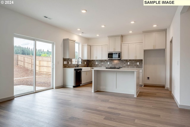 kitchen featuring a center island, light wood-type flooring, stainless steel appliances, and tasteful backsplash