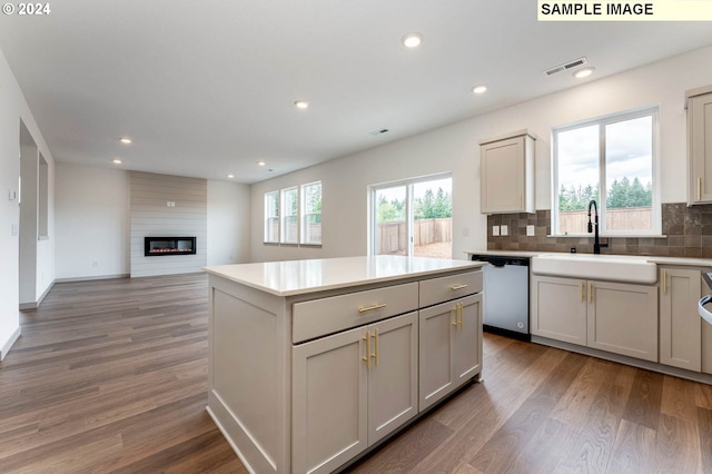 kitchen with stainless steel dishwasher, a wealth of natural light, dark wood-type flooring, and sink