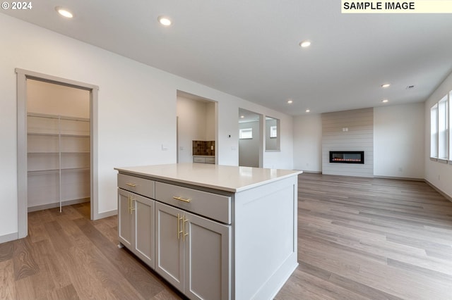 kitchen featuring gray cabinets, a center island, light wood-type flooring, and a fireplace