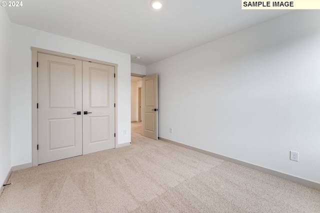 unfurnished bedroom with light colored carpet and a closet