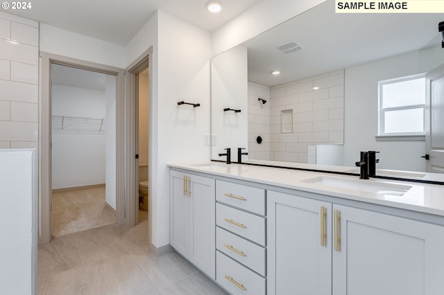 bathroom featuring tiled shower, tile patterned flooring, vanity, and toilet