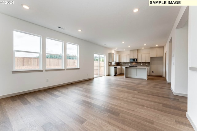 unfurnished living room featuring light wood-type flooring and sink