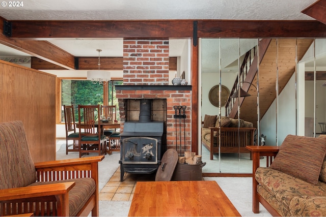 living room featuring a textured ceiling, a wood stove, and beam ceiling