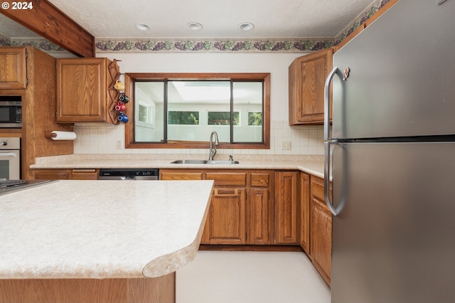 kitchen with decorative backsplash, stainless steel appliances, sink, and beam ceiling