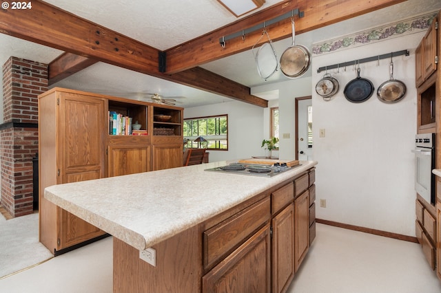 kitchen with stainless steel appliances, a center island, a textured ceiling, light carpet, and beam ceiling