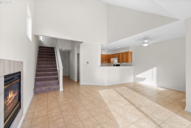 unfurnished living room with light tile patterned floors, ceiling fan, and a high ceiling