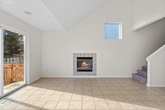 unfurnished living room with a tile fireplace, plenty of natural light, light tile patterned floors, and lofted ceiling