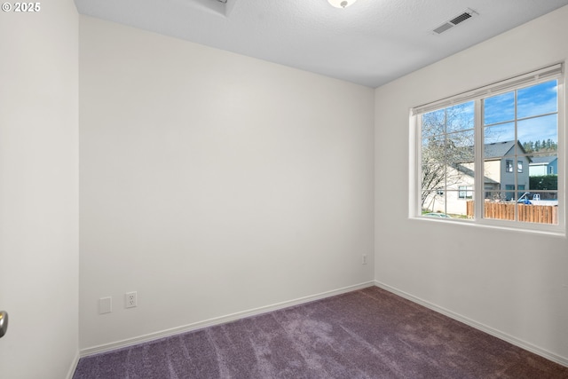 empty room with dark carpet and a textured ceiling