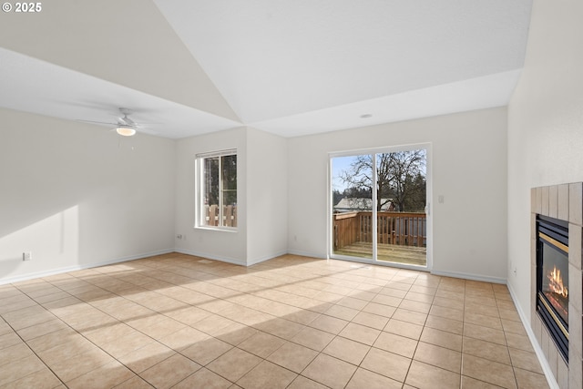 unfurnished living room with a tile fireplace, lofted ceiling, light tile patterned floors, and ceiling fan