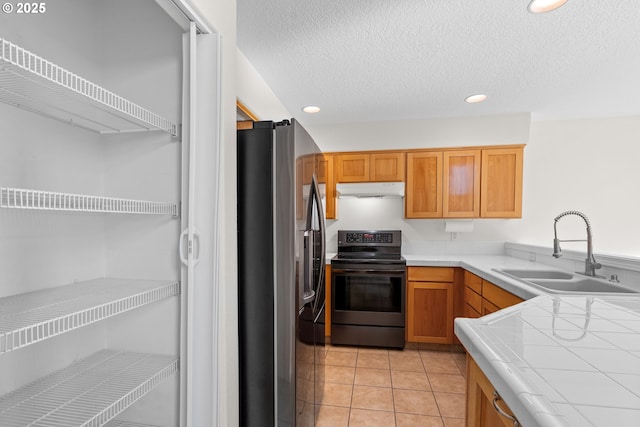 kitchen featuring sink, black electric range, light tile patterned flooring, stainless steel fridge with ice dispenser, and tile countertops