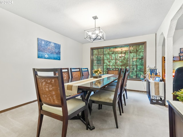 dining space with light carpet, a textured ceiling, baseboards, and a notable chandelier