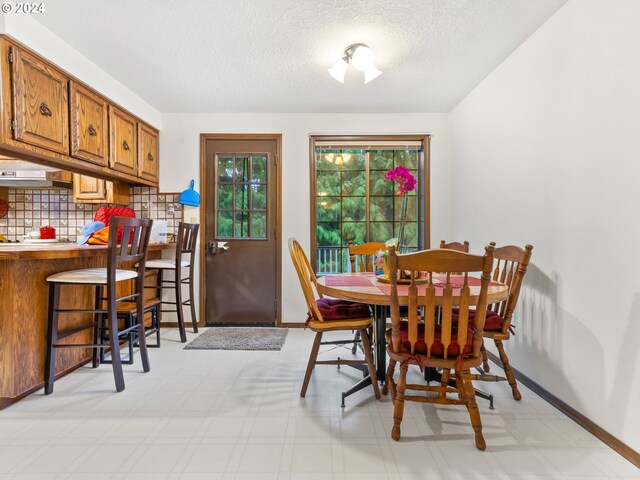 dining room featuring baseboards, a textured ceiling, and light floors