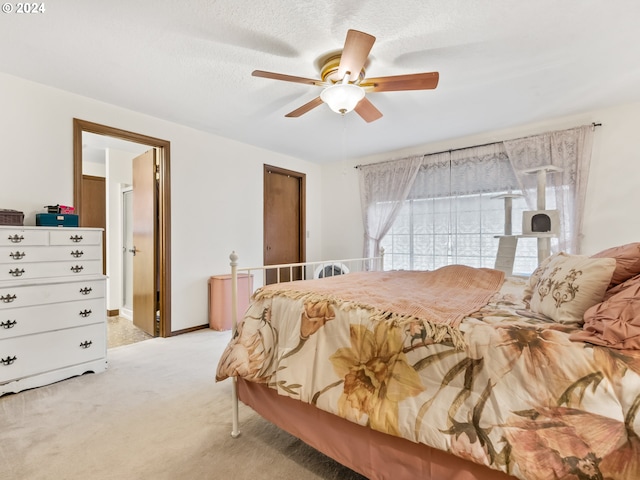 bedroom with a ceiling fan, light colored carpet, a textured ceiling, and baseboards