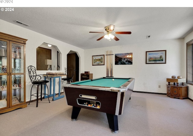 game room with arched walkways, a textured ceiling, visible vents, and light colored carpet