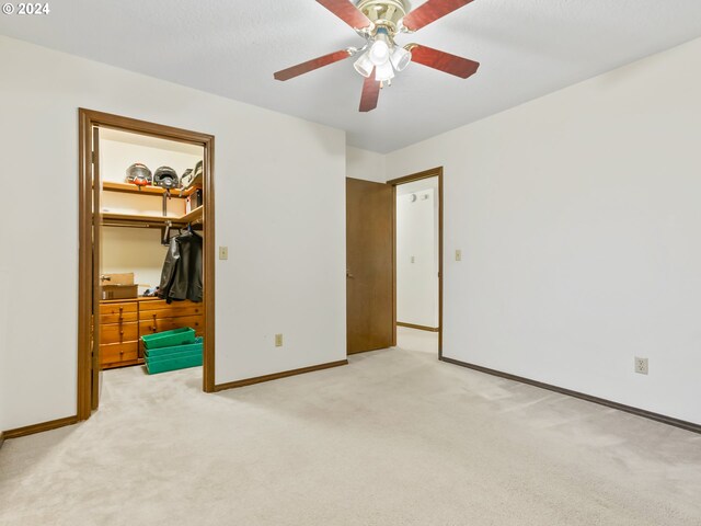 unfurnished bedroom with a closet, a spacious closet, baseboards, and carpet flooring