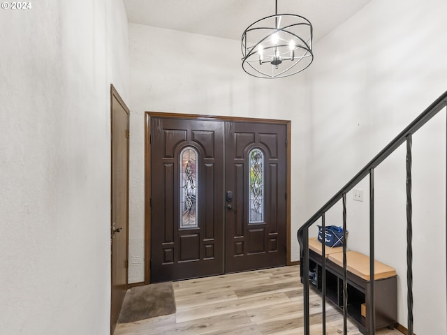 foyer entrance with light wood-style floors, stairs, and a notable chandelier