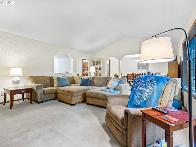 living area with lofted ceiling, carpet, and arched walkways