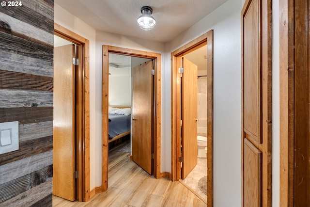 hallway with light hardwood / wood-style floors and a textured ceiling