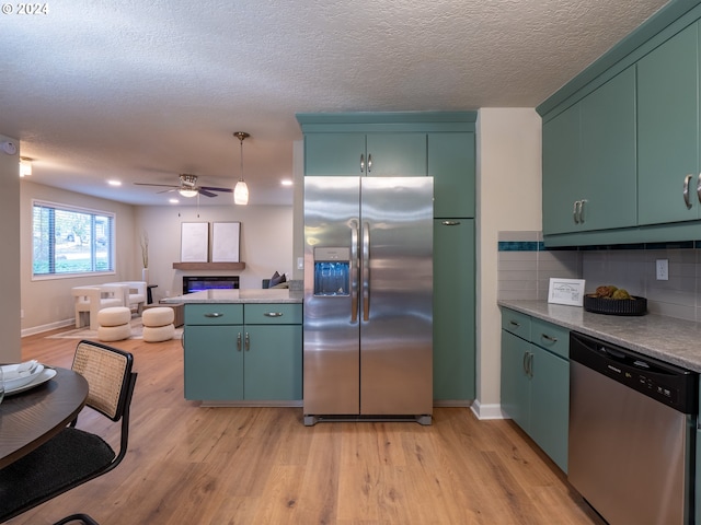 kitchen with green cabinetry, ceiling fan, tasteful backsplash, light wood-type flooring, and appliances with stainless steel finishes