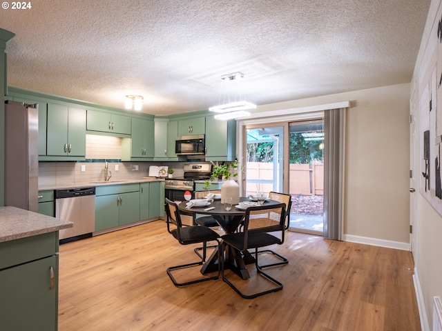 kitchen featuring stainless steel appliances, green cabinetry, light hardwood / wood-style flooring, and sink