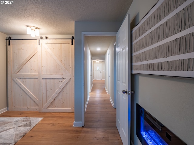 hall featuring a textured ceiling, hardwood / wood-style flooring, and a barn door