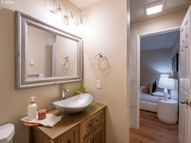 bathroom with toilet, vanity, and hardwood / wood-style floors