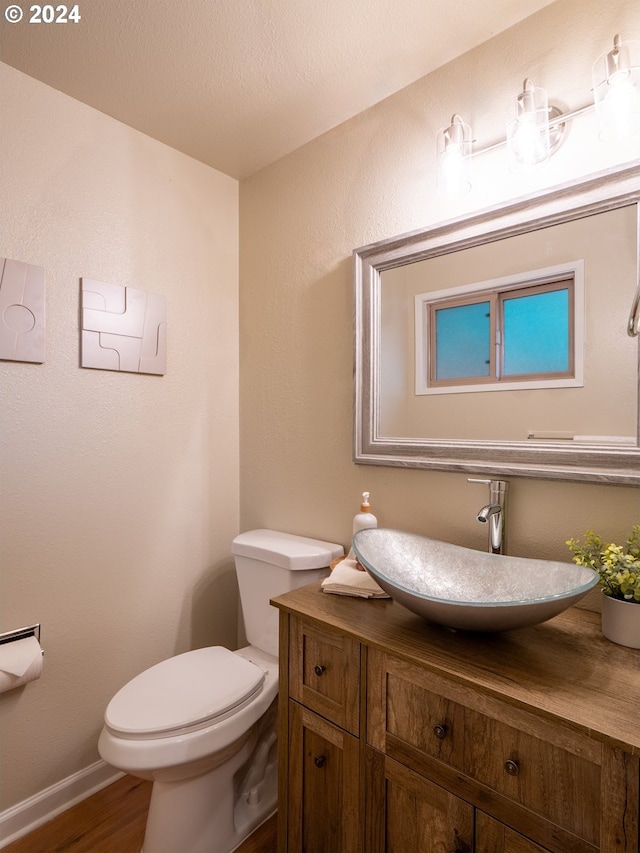 bathroom featuring toilet, vanity, and hardwood / wood-style floors