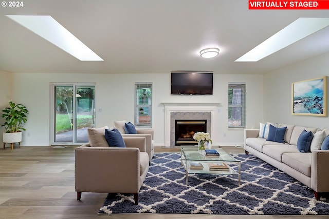 living area featuring wood finished floors, a skylight, a fireplace, and baseboards