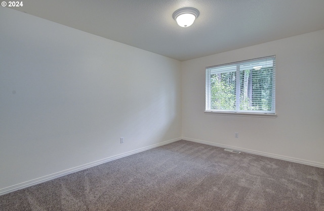 unfurnished room featuring visible vents, carpet, and baseboards