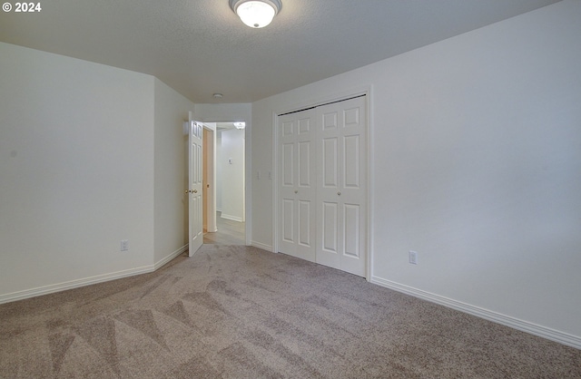 unfurnished bedroom with baseboards, a closet, carpet floors, and a textured ceiling