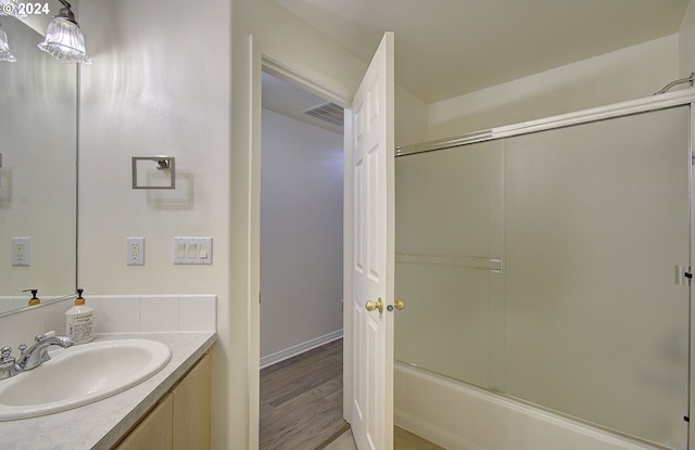 bathroom with visible vents, shower / bath combination with glass door, vanity, and wood finished floors