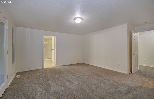 unfurnished room featuring visible vents, carpet flooring, a textured ceiling, and baseboards