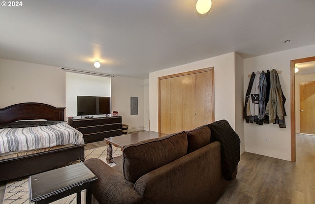 bedroom featuring electric panel, a closet, baseboards, and wood finished floors