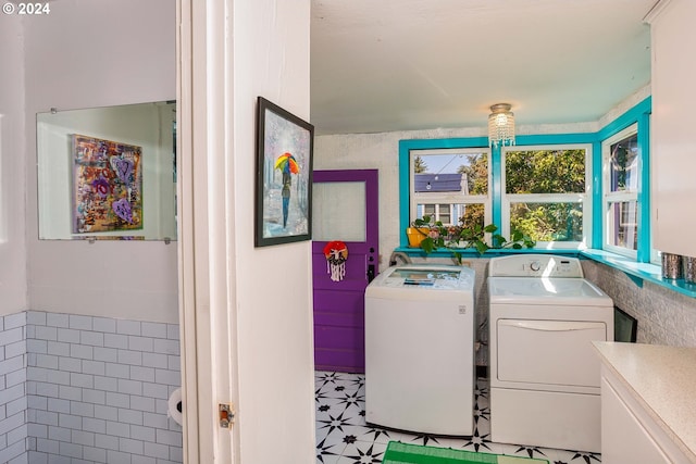 washroom with laundry area, tile walls, washer and dryer, and tile patterned floors