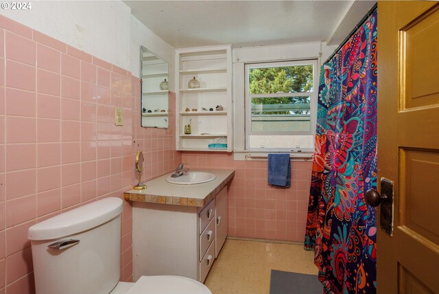 bathroom featuring vanity, toilet, curtained shower, and tile walls