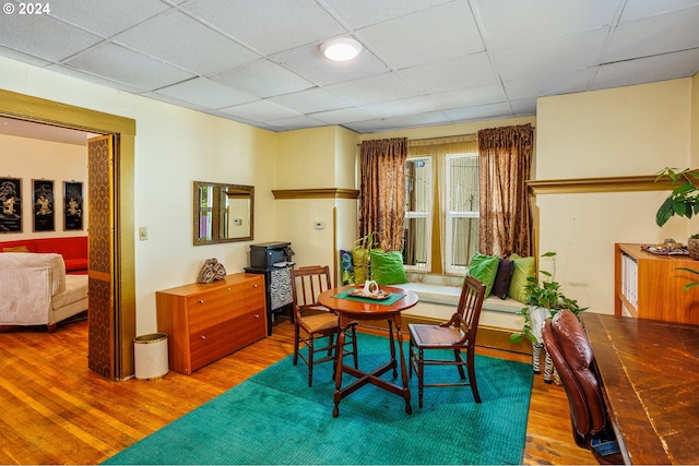 dining space with a drop ceiling and wood finished floors