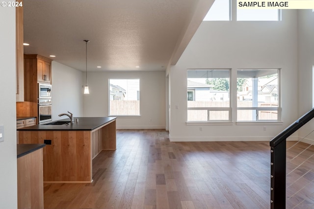 kitchen featuring sink, hanging light fixtures, stainless steel appliances, dark hardwood / wood-style flooring, and a textured ceiling