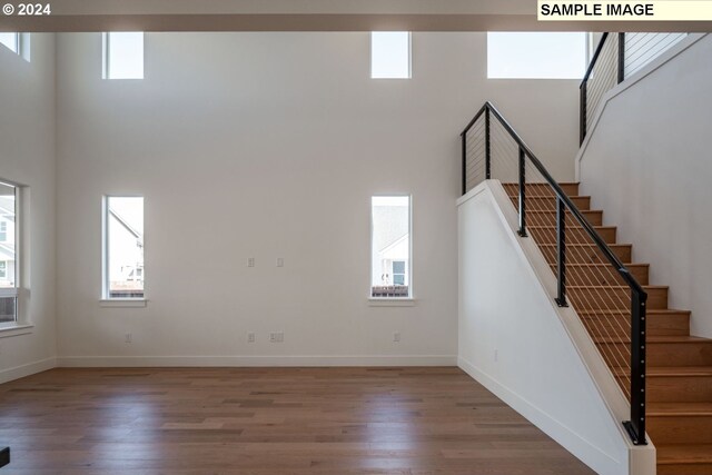 stairs featuring a towering ceiling, hardwood / wood-style flooring, and plenty of natural light