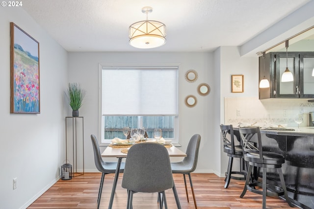 dining space with indoor bar, hardwood / wood-style floors, and a textured ceiling