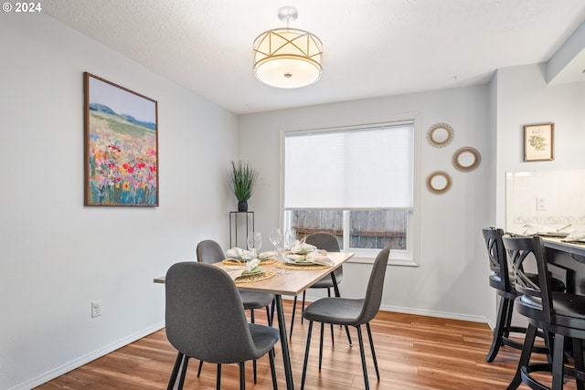 dining space with hardwood / wood-style floors and a textured ceiling