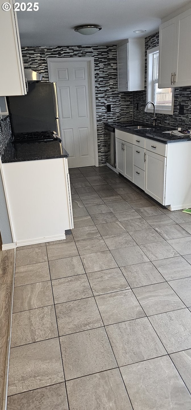 kitchen with sink, stainless steel refrigerator, white cabinets, and backsplash