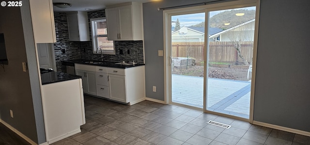 kitchen featuring white cabinets, a healthy amount of sunlight, and decorative backsplash