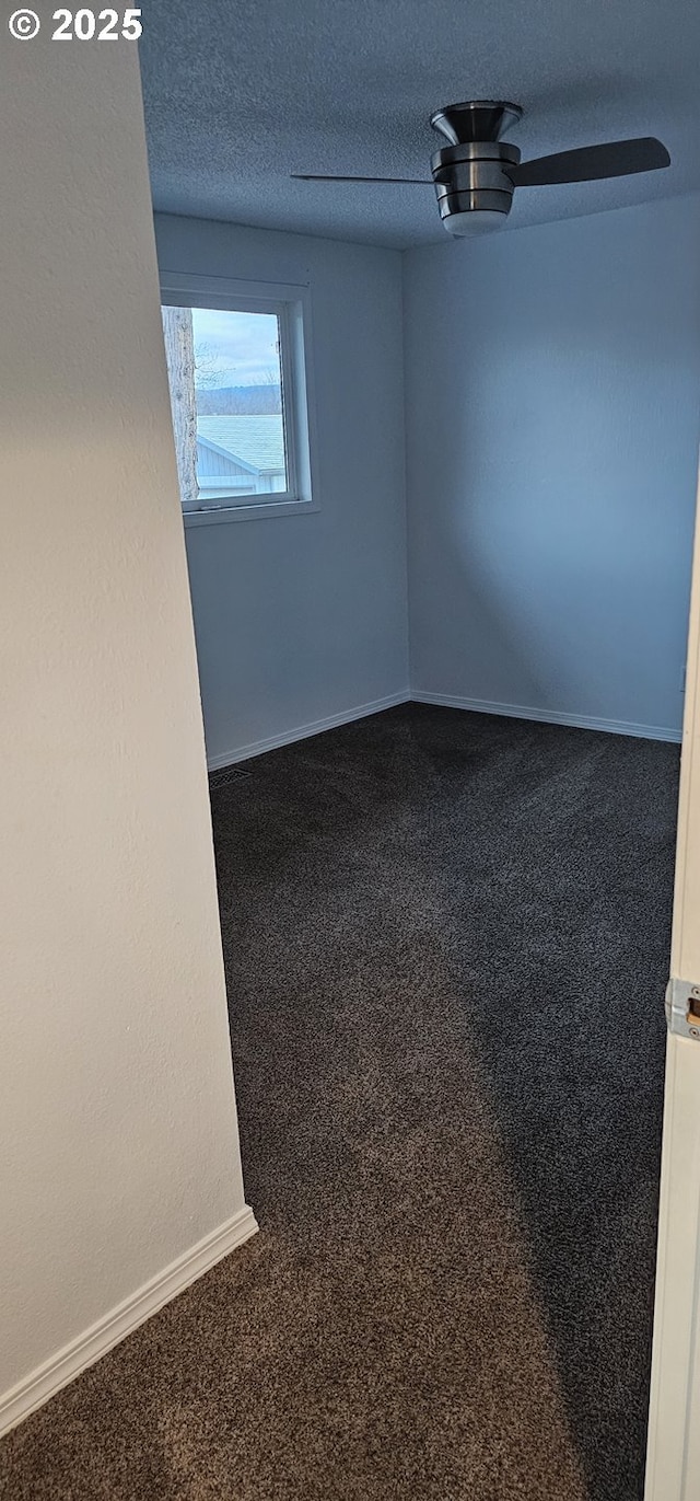 carpeted empty room featuring ceiling fan and a textured ceiling