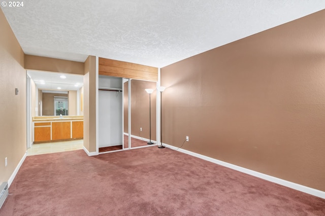 unfurnished bedroom featuring a textured ceiling, carpet floors, and a closet