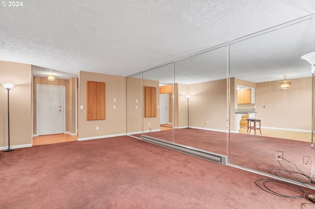 interior space featuring a textured ceiling, carpet floors, and a baseboard heating unit