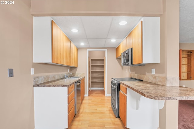 kitchen featuring kitchen peninsula, a breakfast bar, built in shelves, stainless steel appliances, and sink