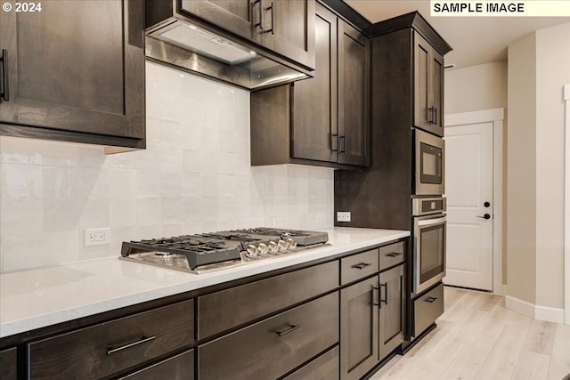 kitchen with dark brown cabinetry, light wood-type flooring, stainless steel appliances, and tasteful backsplash